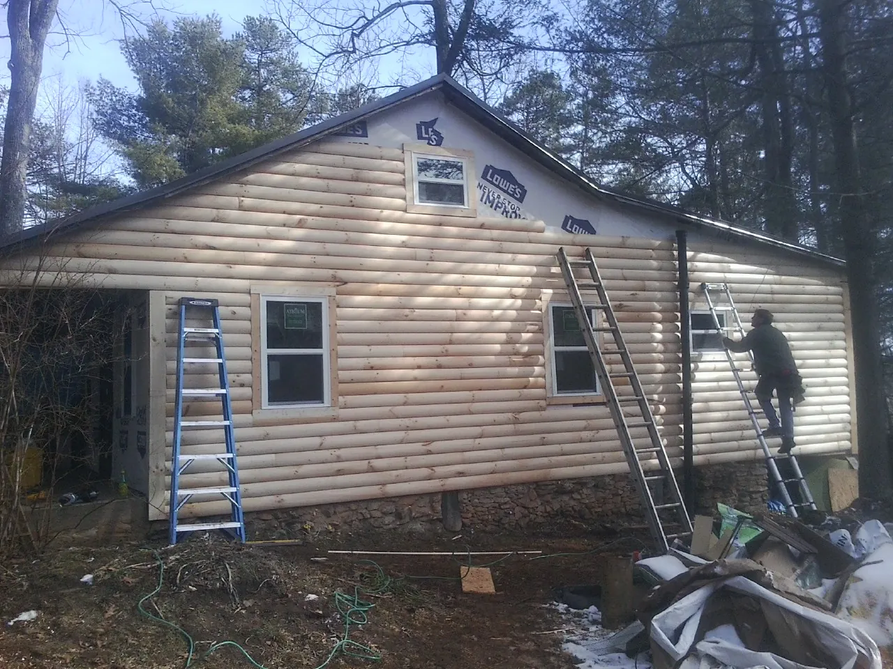 Ladders set against fresh log siding during an exterior remodel in Waterbury