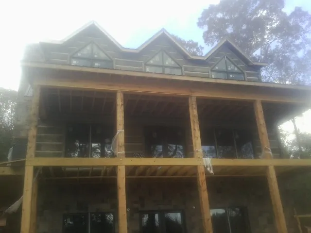 Dormers and porch framing on a large log home under construction — Roof Coating work by our crew in Waterbury