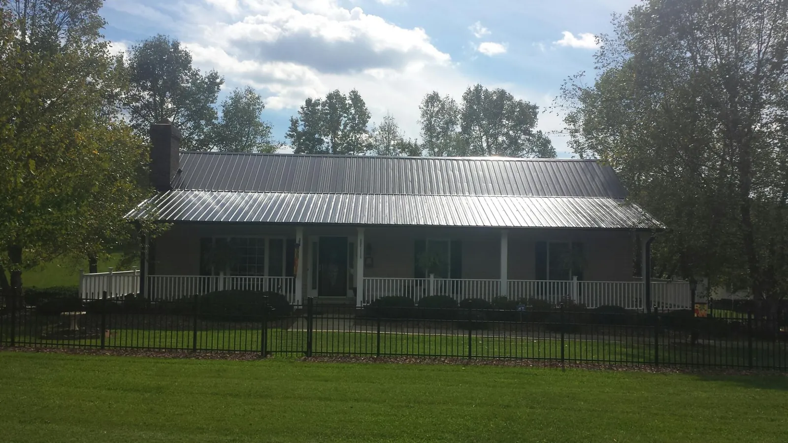 Gray metal roof on a brick ranch with a full width front porch — Gutter Guard Installation work by our crew in Waterbury